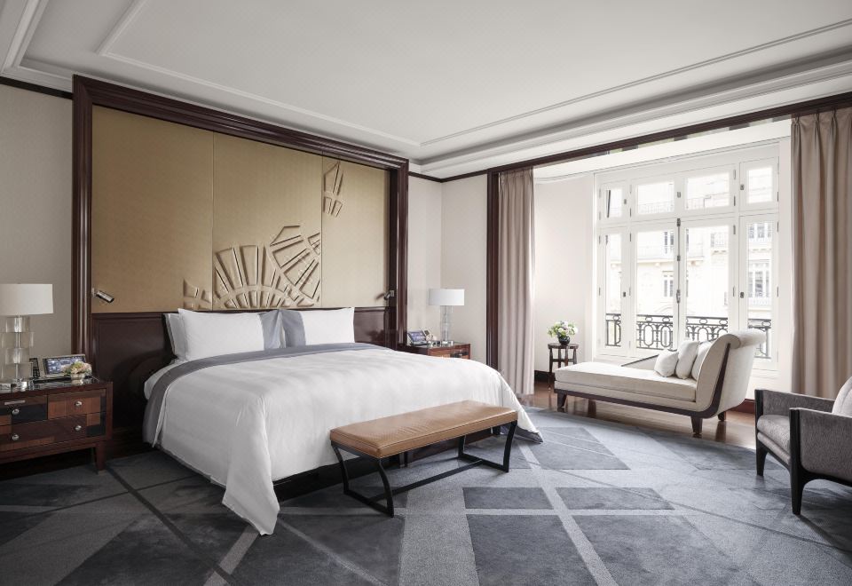a large bedroom with a king - sized bed , a couch , and a window overlooking the outdoors at Hotel the Peninsula Paris