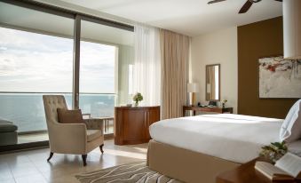 a spacious hotel room with a large bed , a desk , and a window overlooking the ocean at Jumeirah Port Soller Hotel and Spa