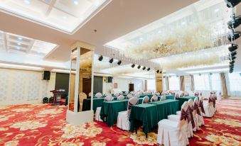a large banquet hall with numerous tables covered in green tablecloths and chairs arranged for a formal event at Victoria International Hotel