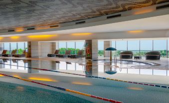 The interior of the hotel includes a spacious pool and floor-to-ceiling windows that provide a view of the indoor area at Four Points by Sheraton Qingdao, West Coast