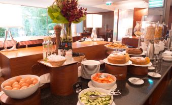 There is a table with various types of food placed on top of the counter, arranged next to each other at VIP Executive Arts Hotel