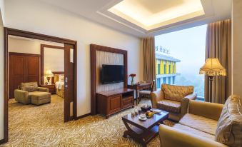 a modern living room with a large window , brown furniture , and a flat - screen tv on the wall at Grand Artos Hotel & Convention