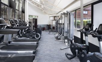 a well - equipped gym with various exercise equipment , such as treadmills , stationary bikes , and weight machines at Delta Hotels Waltham Abbey