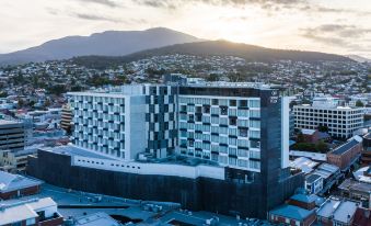 a large hotel with a black and white exterior is situated in a city with mountains in the background at Crowne Plaza Hobart, an IHG Hotel