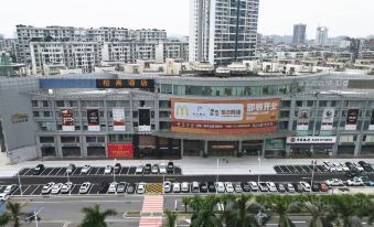 A large building with cars parked in front and other traffic on the street outside at Paco  Hotel (Jiangmen Xinhui Times)