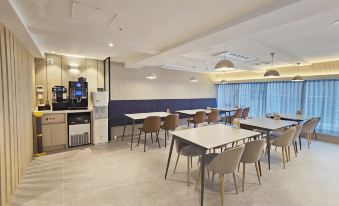 a modern cafeteria with tables , chairs , and a coffee machine , as well as chairs and cabinets in the space at Hotel Foret Premier Nampo