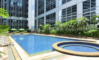 A swimming pool with blue water is surrounded by tall buildings in the background, complemented by lush green shrubs at Harbour Plaza North Point