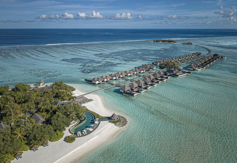 aerial view of a tropical island with multiple overwater bungalows , surrounded by clear blue water at Four Seasons Resort Maldives at Kuda Huraa