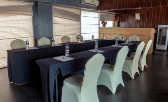 a conference room set up for a meeting , with tables and chairs arranged in a semicircle at Louis Kienne Hotel Simpang Lima