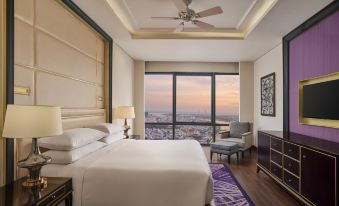 a luxurious hotel room with a king - sized bed , a large window offering a city view , and a wooden floor at Sheraton Can Tho