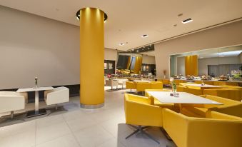 In the center of the restaurant, there are yellow chairs and tables arranged in a way that they all face each other at Jinjiang Inn (Shanghai People's Square East Huaihai Road)