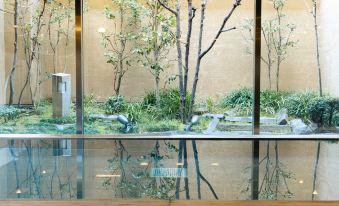 a bird sanctuary with multiple birds perched on rocks and trees in front of a glass wall at Mitsui Garden Hotel Okayama