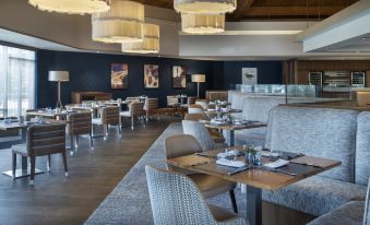 a modern restaurant with wooden tables , chairs , and pendant lights , creating an elegant atmosphere for diners at Delta Hotels Waltham Abbey