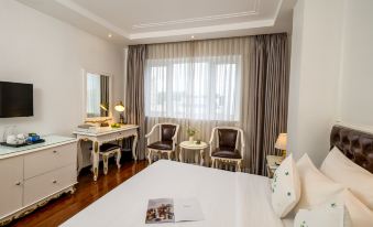 a large bed with a magazine on it is in a room with two chairs and a desk at Alagon Saigon Hotel & Spa