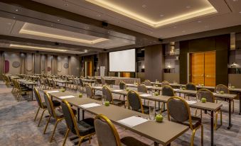 a conference room with rows of tables and chairs , a projector screen , and chairs arranged in a semicircle at Vienna Marriott Hotel