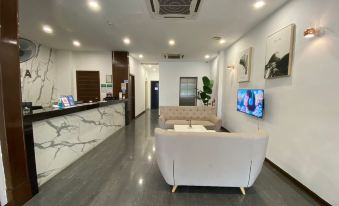 a modern office lobby with white walls , gray flooring , and a marble reception desk at Havona Hotel - Kulai