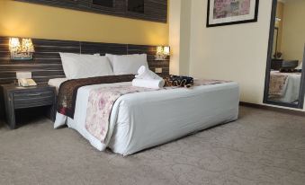 a bed with a white comforter and brown blanket is in a room with carpeted floor at HIG Hotel