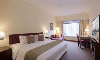 The bedroom is furnished with a bed, desk, and large windows in the middle at Prudential Hotel