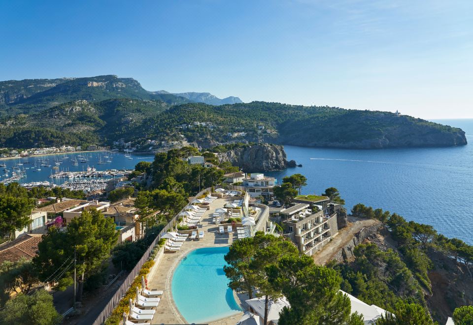 a beautiful resort with a large pool surrounded by trees and mountains , providing a serene view of the surrounding landscape at Jumeirah Port Soller Hotel and Spa