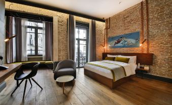 a cozy bedroom with a brick wall , hardwood floors , and a large bed , as well as a desk and a chair in the room at Hotel the Public - Special Category