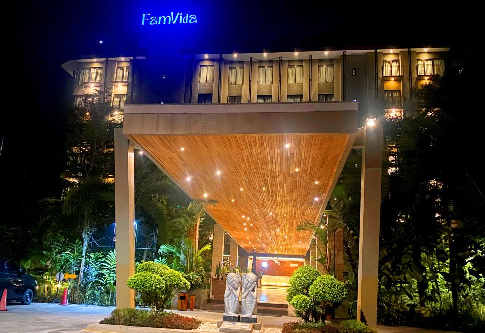 a wooden entrance to a building with a large sign above it , illuminated by lights at FamVida Hotel Lubuklinggau Powered by Archipelago