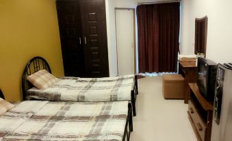 a room with two beds , one on the left and one on the right side of the room at Thanarom Place