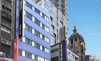 a tall building with multiple windows and a large advertisement for the le room hotel is surrounded by other buildings at Le Room Hotel Taoyuan