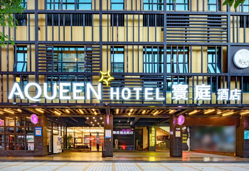 "the exterior of a hotel with a large sign that reads "" queen hotel "" in both english and chinese" at AQUEEN HOTEL