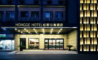At night, a hotel entrance is adorned with an illuminated sign above its glass door at Hongge Apartment Hotel