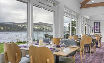 a restaurant with large windows overlooking a body of water , creating a serene and inviting atmosphere at The Kenmore Club