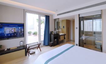 A spacious bedroom with a balcony is available for rent in a hotel or motel, featuring a large bed at Qingdao  Litian Hotel