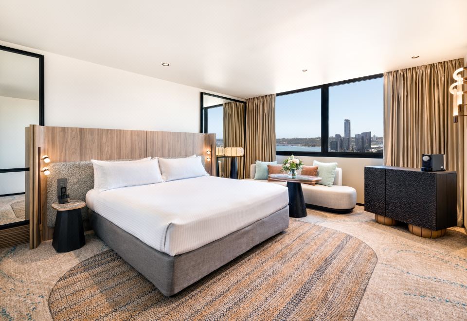 a large bed with white sheets is in a room with a window and a couch at Pan Pacific Perth