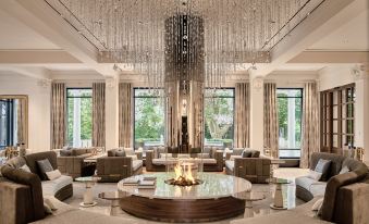 a luxurious living room with a large round fire pit in the center , surrounded by multiple couches and chairs at Grand Resort Bad Ragaz