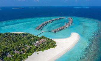 aerial view of a sandy beach with a wooden pier extending into the ocean , surrounded by clear blue water at Anantara Kihavah Maldives Villas