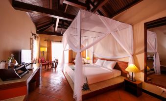 a large bed with a white canopy is in the middle of a room with red tile flooring at Victoria Nui Sam Lodge