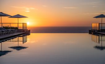 a large infinity pool with a gazebo on the edge and the ocean in the background at Jumeirah Port Soller Hotel and Spa