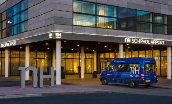 "a blue van is parked in front of a hotel with the sign "" nh hotels "" on it" at NH Amsterdam Schiphol Airport