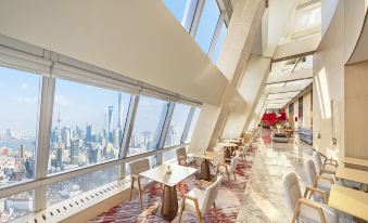 A room on an upper level with large windows and floor-to-ceiling glass offers a scenic view of the city at Conrad Shanghai