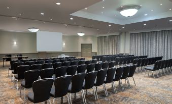 a large conference room with rows of black chairs arranged in a semicircle , ready for a meeting or presentation at Delta Hotels Waltham Abbey