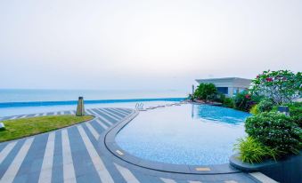 There is a swimming pool located near the ocean, with houses on both sides at Howard Johnson Plaza by Wyndham Blue Bay Sihanoukville