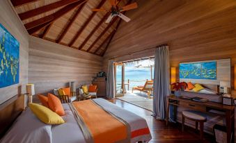 a spacious bedroom with a king - sized bed , a ceiling fan , and a view of the ocean at Mirihi Island Resort