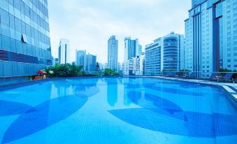 There is a swimming pool with the city skyline in the background and skyscrapers on either side at Crowne Plaza Guangzhou City Centre