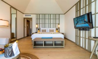a large bedroom with a king - sized bed , a television mounted on the wall , and a door leading to a balcony at Kagi Maldives Resort & Spa