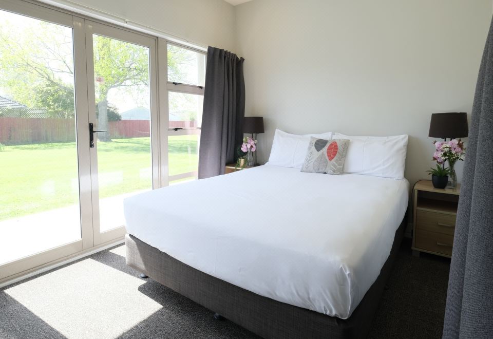 a large white bed with a black headboard and footboard is in a bedroom next to a sliding glass door at Garden Hotel