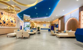 "a modern and elegant lobby with blue ceilings , white couches , and gold decorations , along with the word "" sbe "" on a circular" at TUI BLUE Nha Trang
