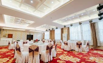 a large banquet hall with multiple round tables covered in white tablecloths and chairs arranged for a formal event at Victoria International Hotel
