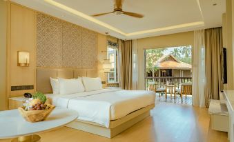 a large bed with white linens is in a room with a ceiling fan and sliding glass doors at Pelangi Beach Resort & Spa, Langkawi