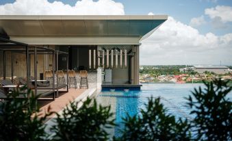 a large swimming pool with a modern design , surrounded by lush greenery and a city view in the background at Zuri Hotel