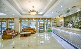 a luxurious hotel lobby with marble floors , gold accents , and large windows , as well as a reception desk and couches at Vienna Hotel