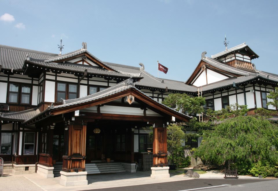 a traditional japanese building with a flag on top , surrounded by trees and clear skies at Nara Hotel